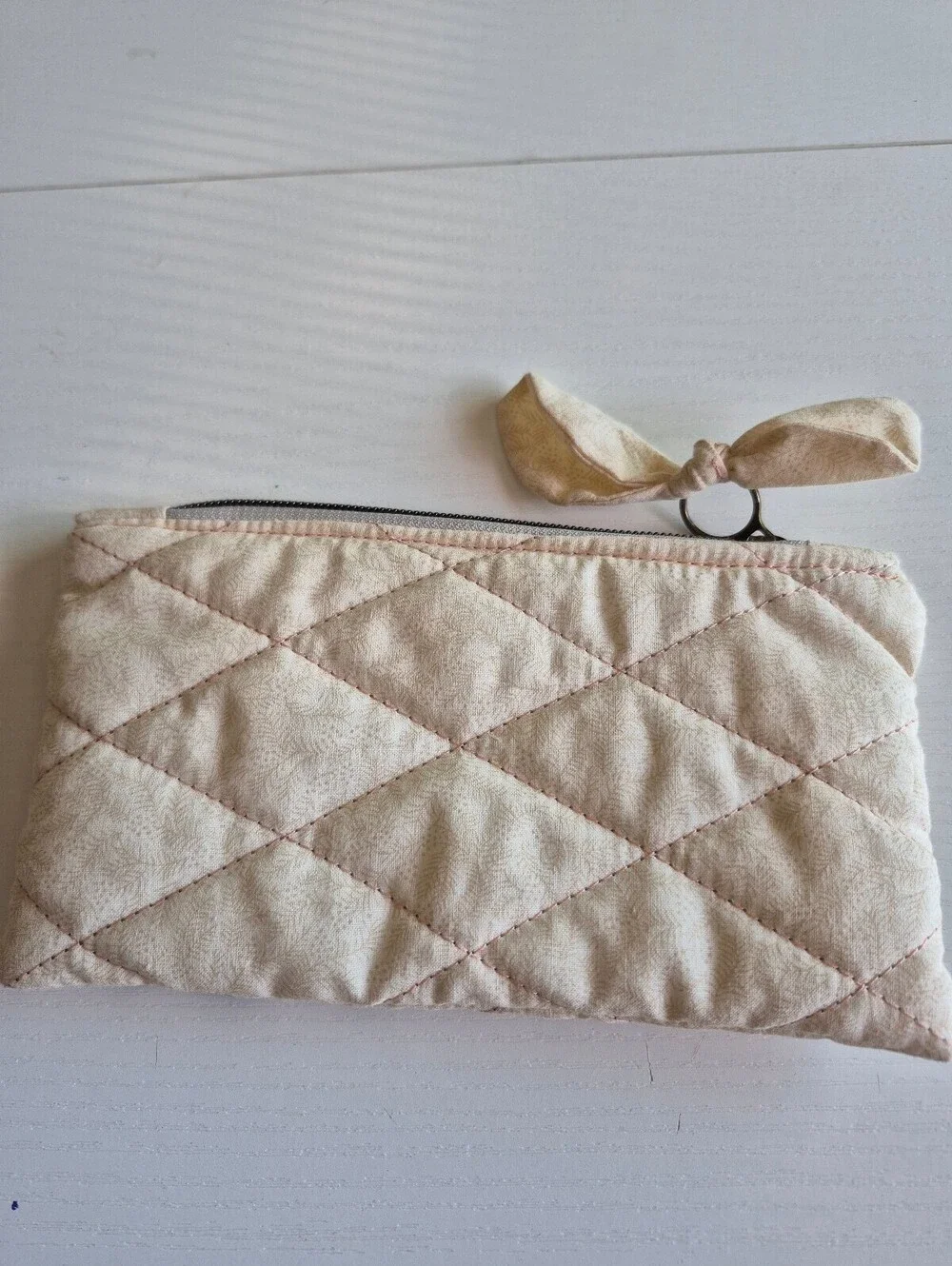 Creme slasher w/ flowers Quilted bow pouch w/ bow zipper pull accent